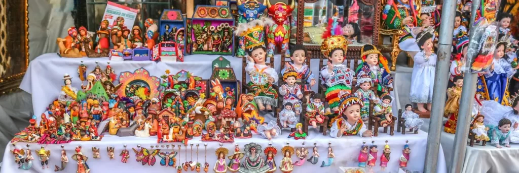 Cusco artisans exhibiting and creating Baby Manuelito figures and Christmas ornaments at the Santurantikuy fair in Cusco's Plaza de Armas.